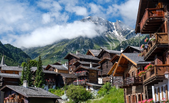 houses in a town right under the mountains with clear blue sky and some clouds